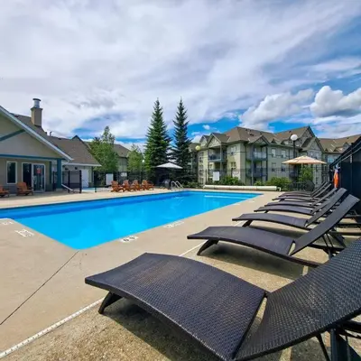a swimming pool with lounge chairs in a resort at Peaks of Radium by StayIn in Radium Hot Springs