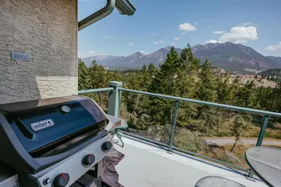a grill on a balcony with a view of mountains at Peaks of Radium by StayIn in Radium Hot Springs