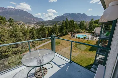 a glass table on a balcony with a view of the mountains at Peaks of Radium by StayIn in Radium Hot Springs