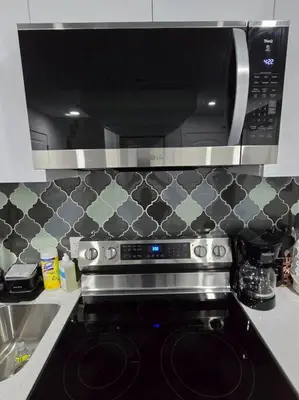 a microwave above a stove in a kitchen at Cozy New 1 bed basement suite in Edmonton