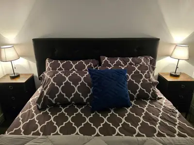 a bed with two lamps and a blue pillow on it at Cozy New 1 bed basement suite in Edmonton