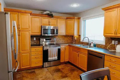 a kitchen with wooden cabinets and stainless steel appliances at Central Calgary & Nearby Mountain Escape - 4 Beds in Calgary