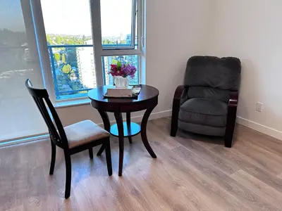 a table and a chair in a living room with a chair and a table at New condo near Lougheed Mall & SFU in Coquitlam