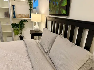 a bedroom with a bed and a table with a lamp at Bright Spacious 3 BR Garden Suite, 4 Queen beds, Fully equipped, Highly recommended by 229 happy groups in Burnaby