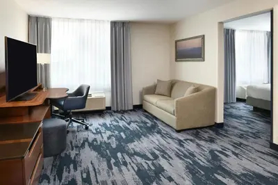 a hotel room with a couch chair and a television at Fairfield Inn & Suites by Marriott Calgary Downtown in Calgary