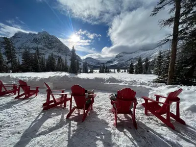 a group of red chairs sitting in the snow at The Lodge at Bow Lake in Lake Louise