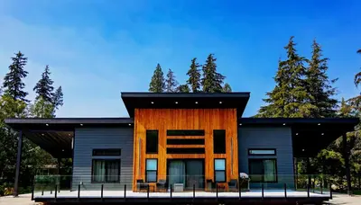 a house with a black roof and a wooden facade at LuxQuarters Bumbleberry Guest House in Kitimat