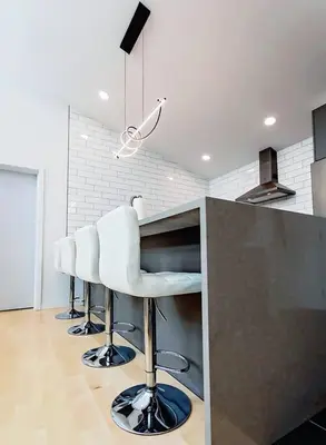 a kitchen with a counter with four white bar stools at LuxQuarters Huckleberry Suite in Kitimat