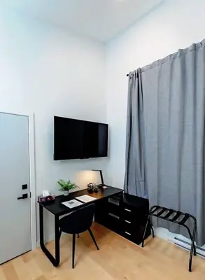 a room with a desk and a television on a wall at LuxQuarters Blueberry Studio in Kitimat