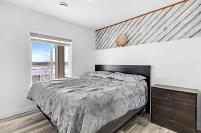 a bedroom with a large bed and a window at Serenity&Luxury Redefined - A waterfront adventure in Airdrie
