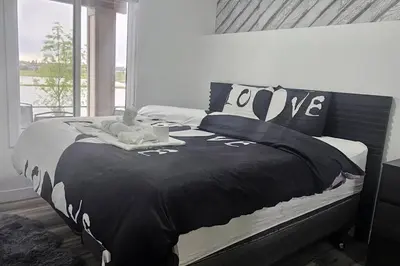 a bedroom with a bed with a black and white comforter at Serenity&Luxury Redefined - A waterfront adventure in Airdrie