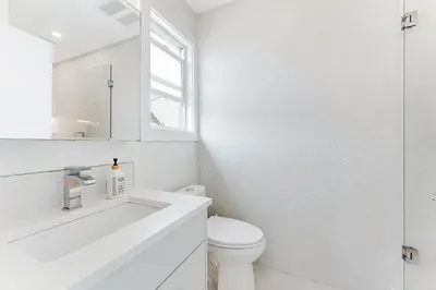 a white bathroom with a toilet and a sink at Riley Park-Modern 4 Bedroom Home, Central location in Vancouver