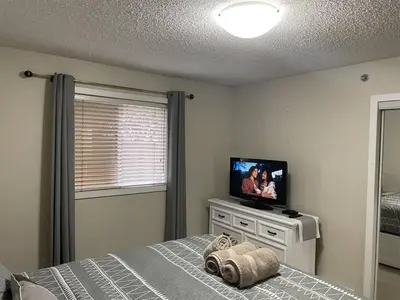 a bedroom with a bed with a flat screen tv at Chris Cozy Condo Commonwealth #107 Edmonton in Edmonton