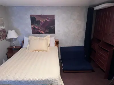 a small bedroom with a bed and a chair at Frankies Westshore Hideaway in Victoria