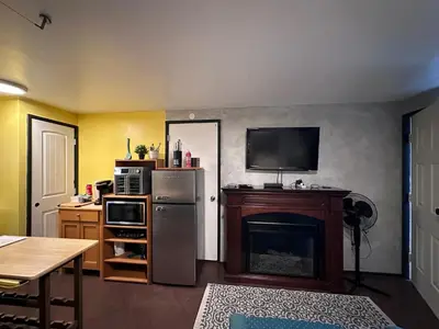 a kitchen with a refrigerator and a tv on a wall at Frankies Westshore Hideaway in Victoria