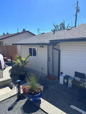 a white house with a garage and some plants at Frankies Westshore Hideaway in Victoria