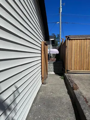 a white siding on a house with a fence at Frankies Westshore Hideaway in Victoria