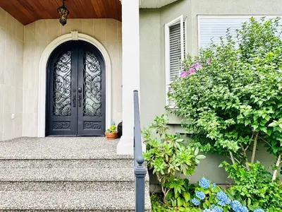 a black door on a house with stairs and flowers at Spacious 5BR 3BA Guest Villa - 10 Min to DT - Pet Friendly, Free Parking in Vancouver