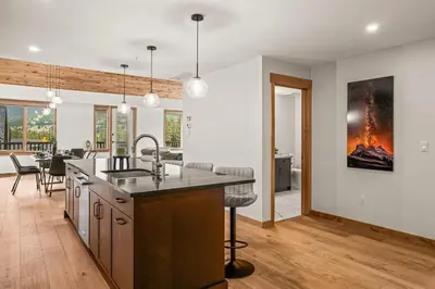 an open kitchen and dining room with a fire painting on the wall at Spring Creek Luxury - managed by Little Sister Getaways in Canmore