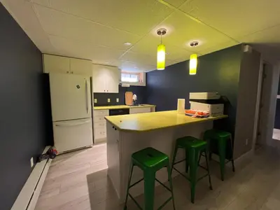 a kitchen with a counter and two green stools at Little Holiday Home in Yellowknife