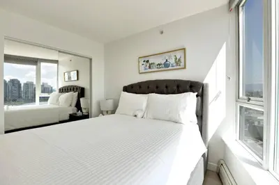 a bedroom with a large white bed and a window at Luxary Condo Downtown Vancouver with free parking in Vancouver