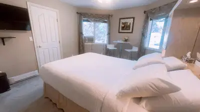 a bedroom with a large white bed and a table at Cornerstone Bed and Breakfast in Revelstoke