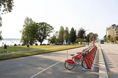 a row of red bikes parked next to a street at Designer 2BR in Downtown Steps from Sunset Beach in Vancouver