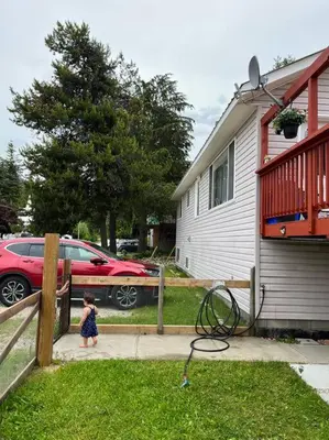 a little girl walking on a sidewalk next to a house at Michaud's Basement unit in Nakusp