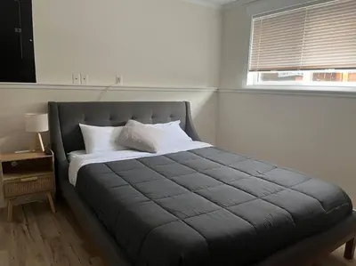 a bed in a white room with a window at Michaud's Basement unit in Nakusp