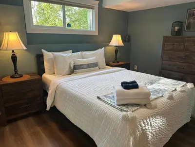 a bedroom with a bed with two lamps and a window at Caribou Lodge in Terrace