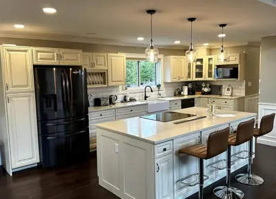a kitchen with white cabinets and a black refrigerator at Caribou Lodge in Terrace