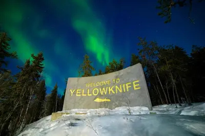 a sign with the words welcome to yellowknife under the northern lights at EC Lodging in Yellowknife