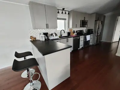 a kitchen with white cabinets and a black counter top at EC Lodging in Yellowknife