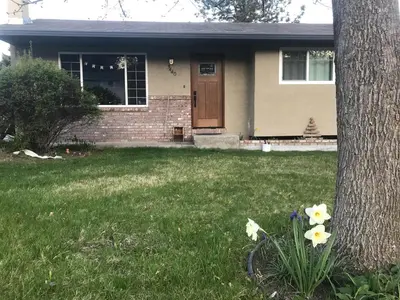 a house with a tree and flowers in the grass at The Musical Perch in Kelowna