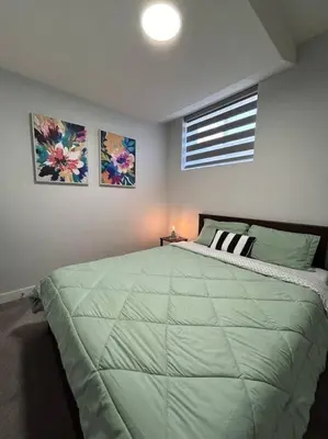 a bedroom with a large green bed with two pictures on the wall at Comfortable and centrally located guest suite in Calgary