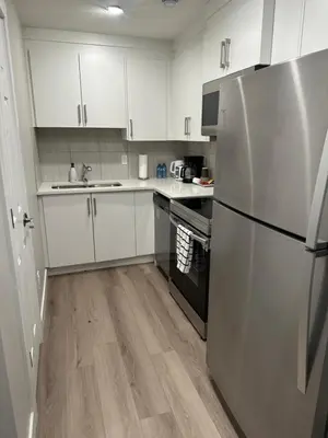 a kitchen with white cabinets and a stainless steel refrigerator at A Luxurious Cozy Place in Calgary