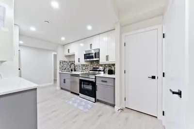 a kitchen with white cabinets and an open door at Executive Bliss Suites in Calgary