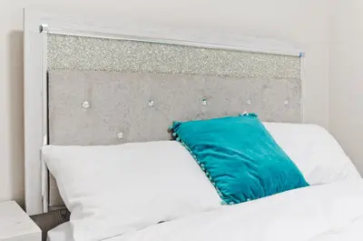 a white bed with a blue pillow on it at Executive Bliss Suites in Calgary
