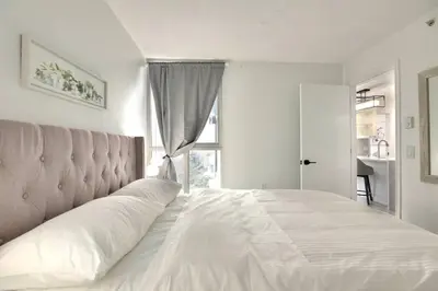 a bedroom with a large white bed with a window at Luxury Condo in Downtown Vancouver with city view in Vancouver