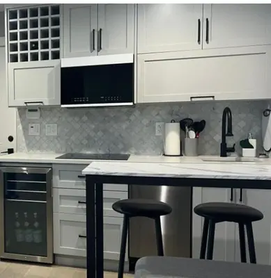 a kitchen with white cabinets and bar stools at Modern West Coast Contemporary Suite in Vancouver