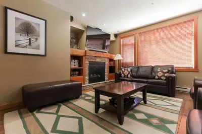 a living room with a leather couch and a table at Slalom Creek 2 Bedroom & Den in Rossland