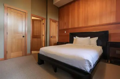a bedroom with a large white bed with wooden walls at Slalom Creek 2 Bedrooms in Rossland