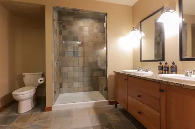 a bathroom with a shower and a toilet and two sinks at Slalom Creek 2 Bedrooms in Rossland