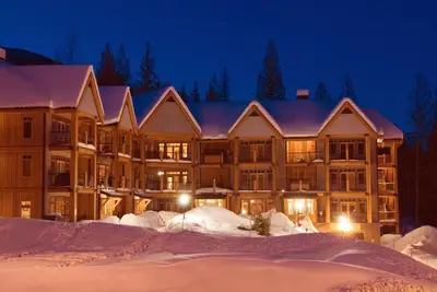 a large building in the snow at night at Silver Tip 2 Bedroom Condo in Rossland