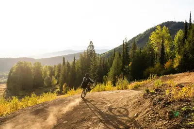 a person riding a bike down a dirt road at White Wolf in Rossland
