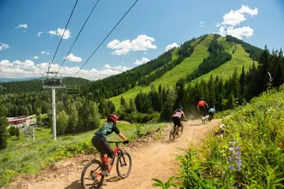 a group of people riding bikes down a dirt road at White Wolf in Rossland