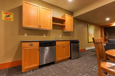 a kitchen with wooden cabinets and a stainless steel dishwasher at Slalom Creek 2 Bedroom & Den in Rossland