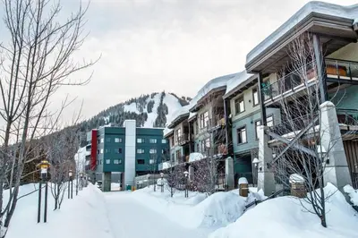 a snow covered street with buildings and a mountain at Slalom Creek 2 Bedroom & Den in Rossland