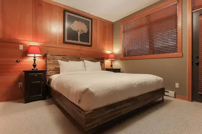 a bedroom with a bed and two lamps and a window at Slalom Creek 2 Bedroom & Den in Rossland