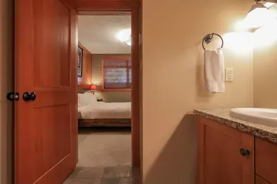 a bathroom with a sink and a bedroom with a bed at Slalom Creek 2 Bedroom & Den in Rossland